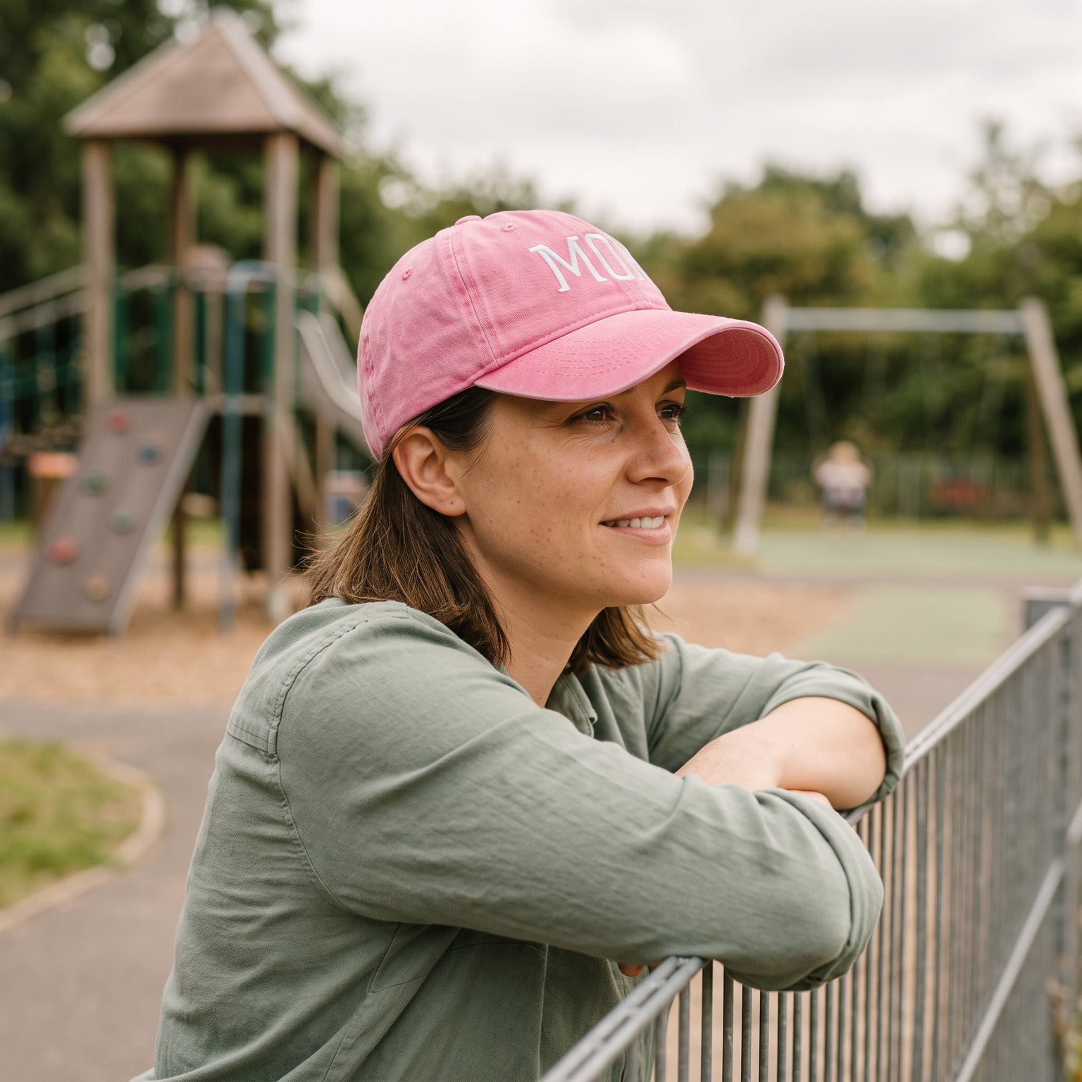 Mum in a Pink MOM cap at the playground