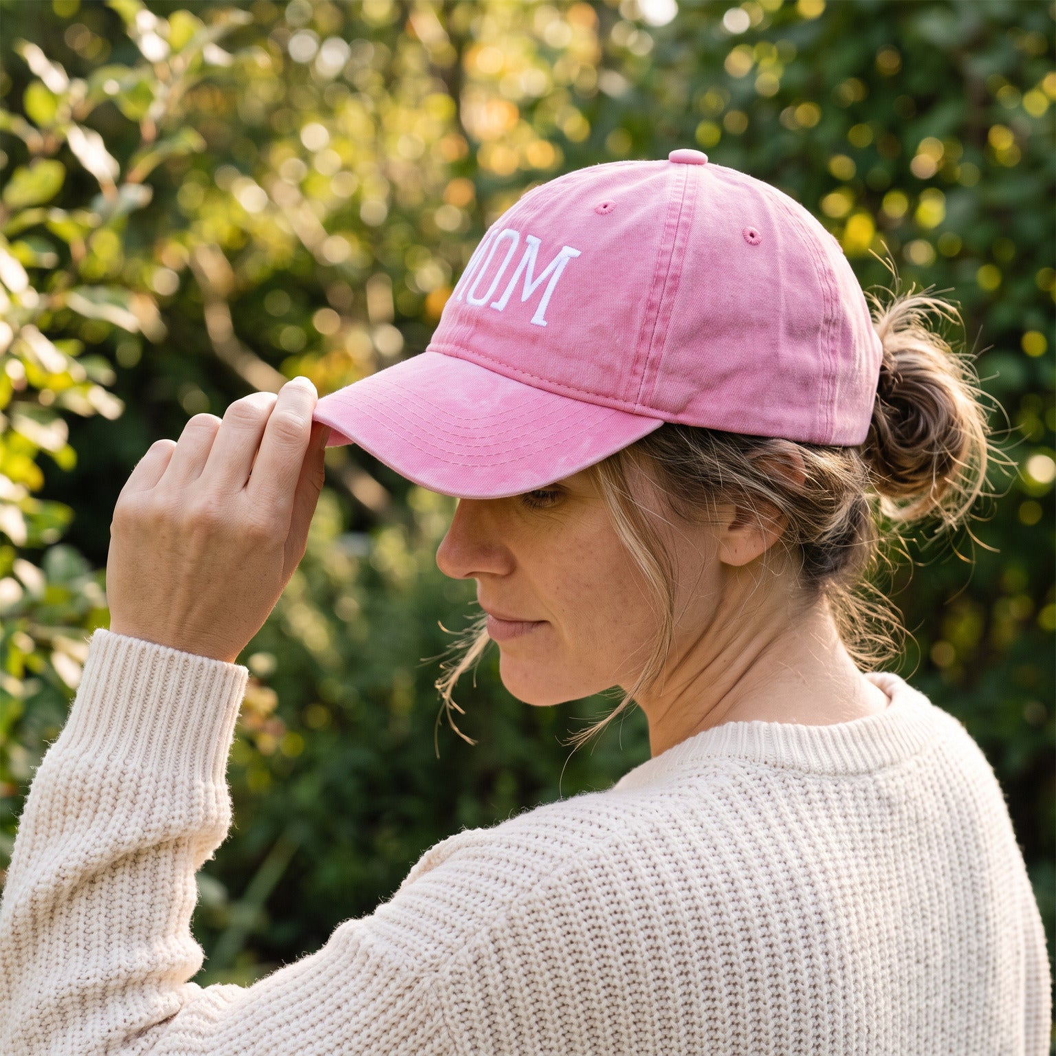 Mum settling the brim of her Pink MOM cap in the garden