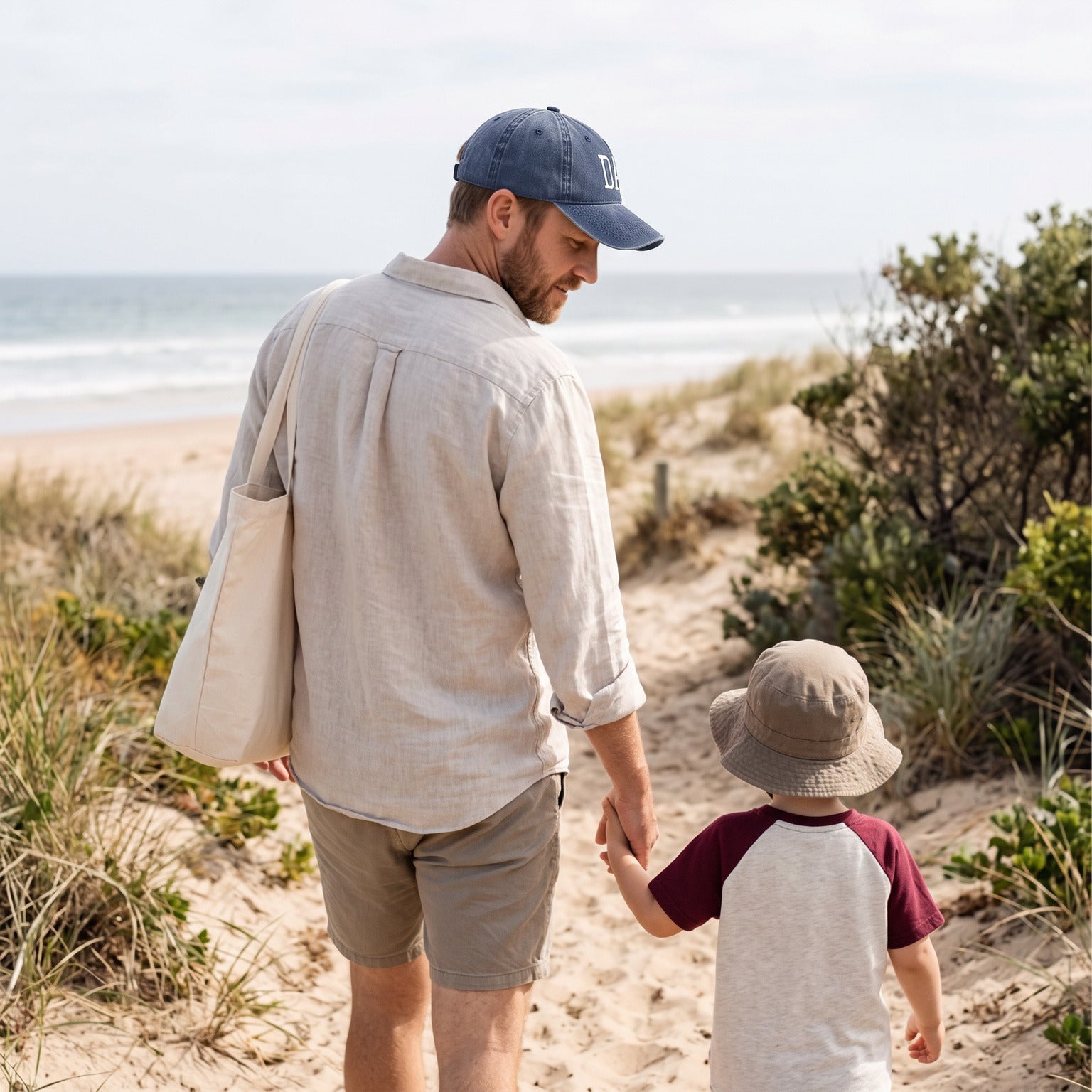 Dad wearing a Blue DAD cap on a beach walk with his child