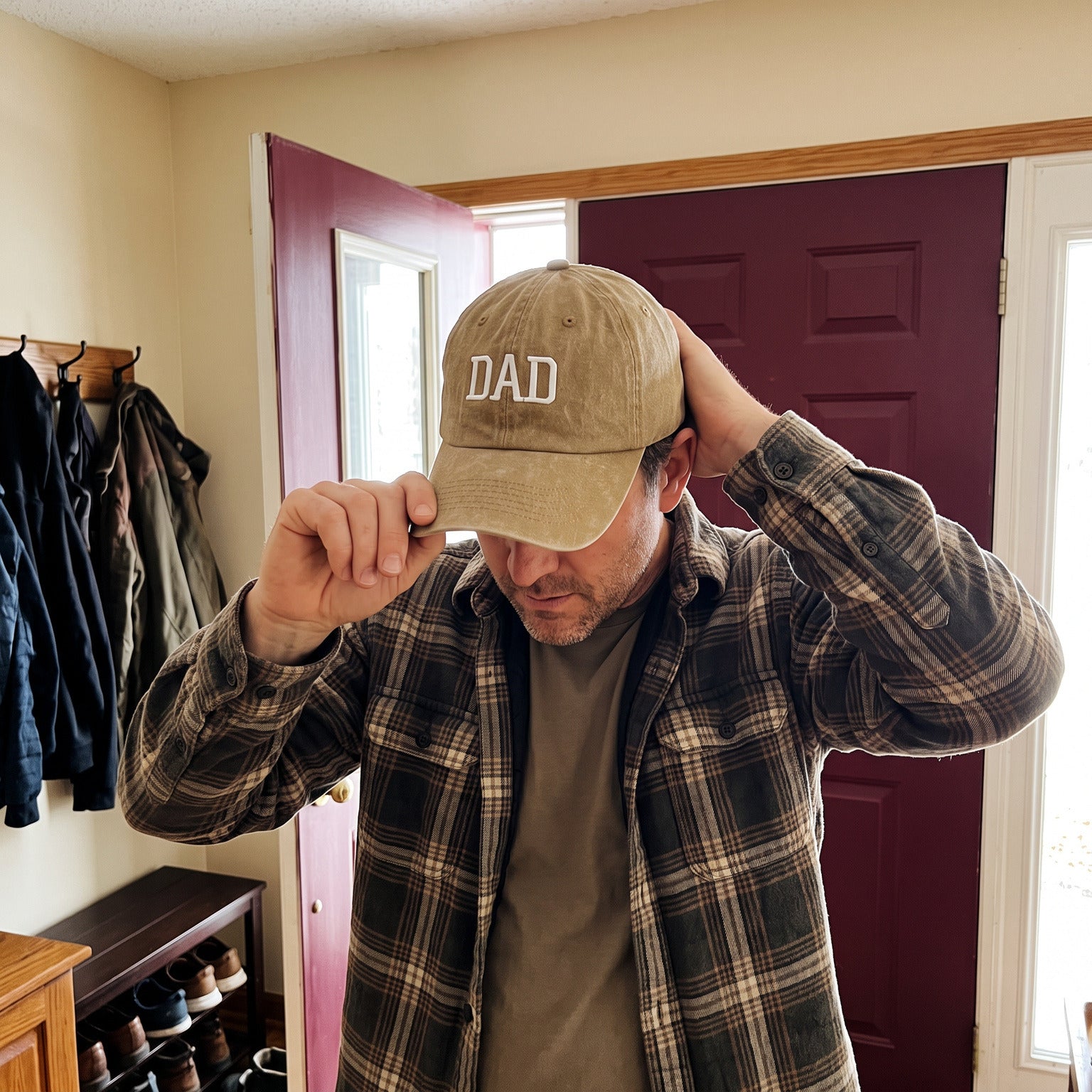 Dad putting on a Khaki DAD cap at the doorway