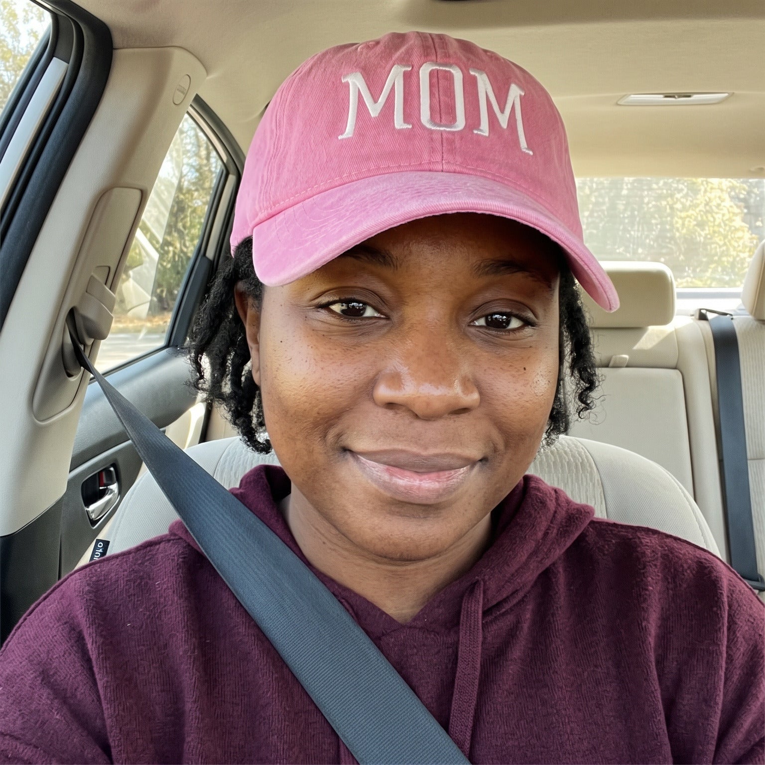 Mum taking a car selfie wearing her Pink MOM cap